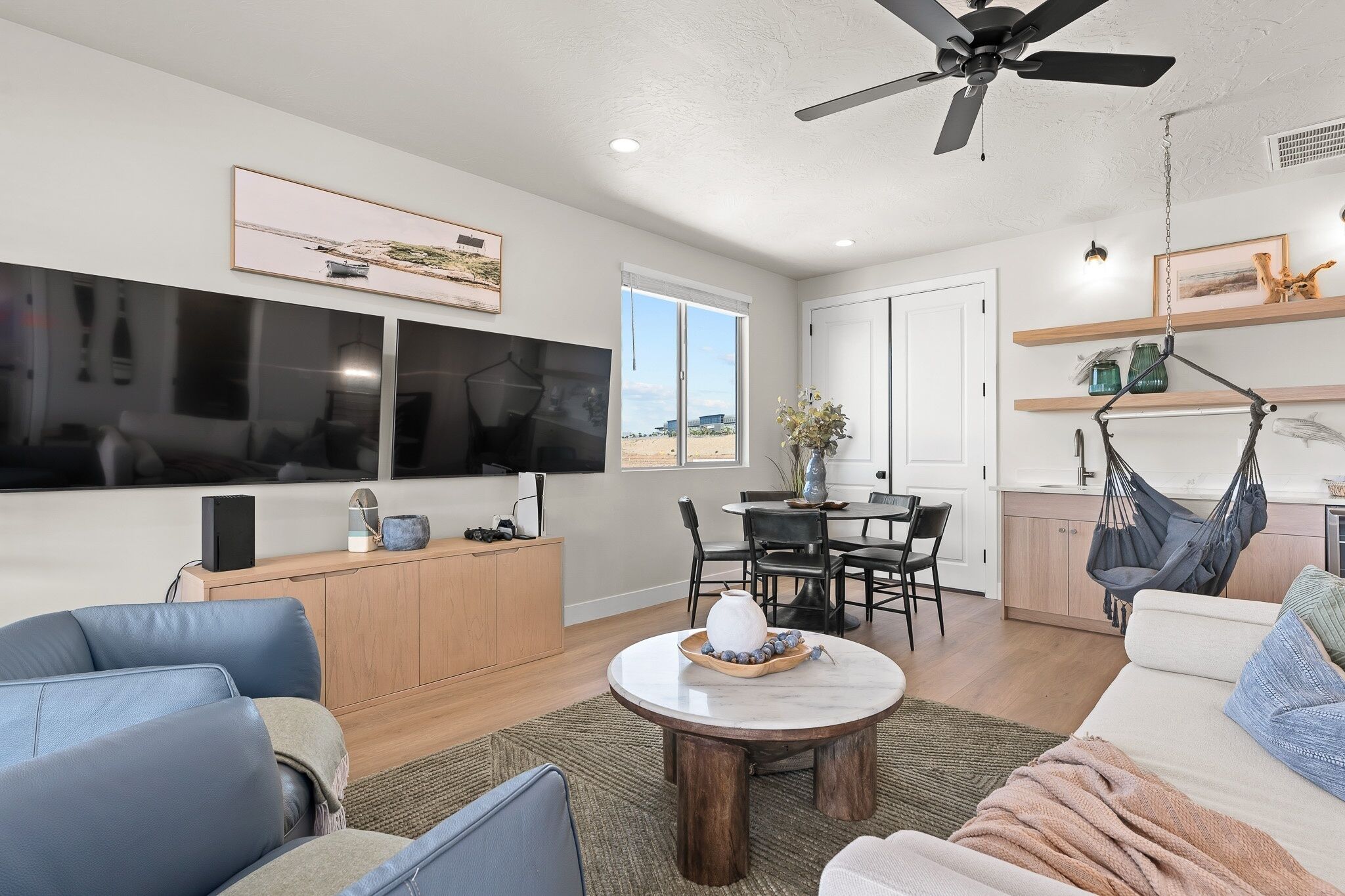 A modern living room with a flat-screen TV, a dining area, and a hammock.