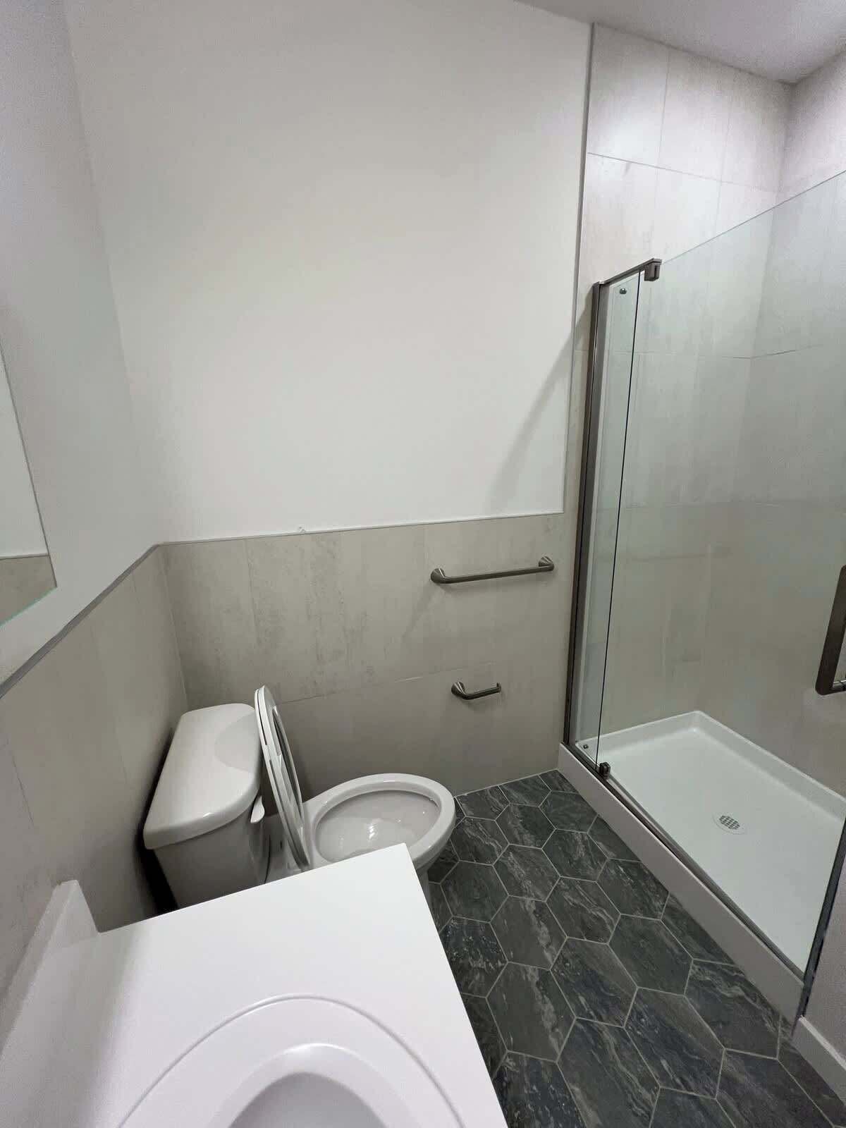 Un baño moderno con inodoro, bidé y zona de ducha con mampara de vidrio.