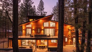 A modern two-story cabin with a wooden exterior, large windows, and a balcony.