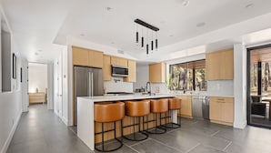 A modern kitchen with a central island, stainless steel appliances, and wooden cabinetry.