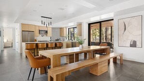 A modern kitchen with a central island, wooden furniture, and a large window providing natural light.