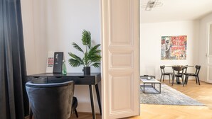 A modern living room with a black sofa, a dining table with chairs, a potted plant, and a painting on the wall. - Rochus Stylish Stays (Vienna)