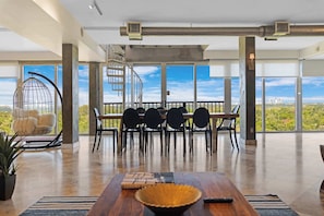 A spacious room with a dining area, large windows, a spiral staircase, and a view of the city.