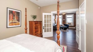 A bedroom with a four-poster bed, a dresser, a door leading to a living area with a sofa and a coffee table. - *New* Monmouth Loft 1 | City Chic 1 BDR (Newport)
