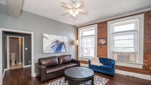 A living room with a brown leather sofa, a blue sofa, a patterned rug, and a ceiling fan. - *New* Monmouth Loft 1 | City Chic 1 BDR (Newport)