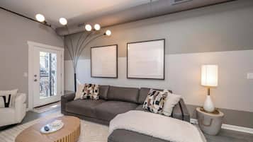 A modern living room with a grey sofa, a white armchair, a wooden coffee table, and a lamp on a side table.