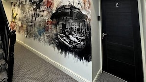 A hallway with a mural depicting a cityscape, a staircase, and a door marked with the number 2.