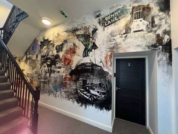A staircase with a wall mural featuring various historical and cultural elements, including a ship and the text 'PENNY LANE.'