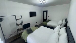 A hotel room with two beds, a TV, a wardrobe, and a ladder.