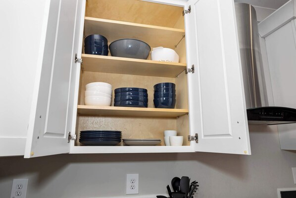 A kitchen cabinet with multiple shelves containing various kitchenware items.