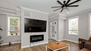 Un salon moderne avec un téléviseur à écran plat fixé au mur, une table basse en bois et un canapé marron.
