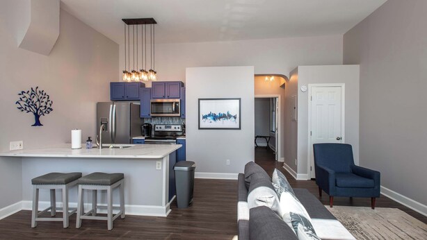 A modern kitchen with a central island, bar stools, and pendant lighting. - Heart of Mainstrasse 1 (Covington)