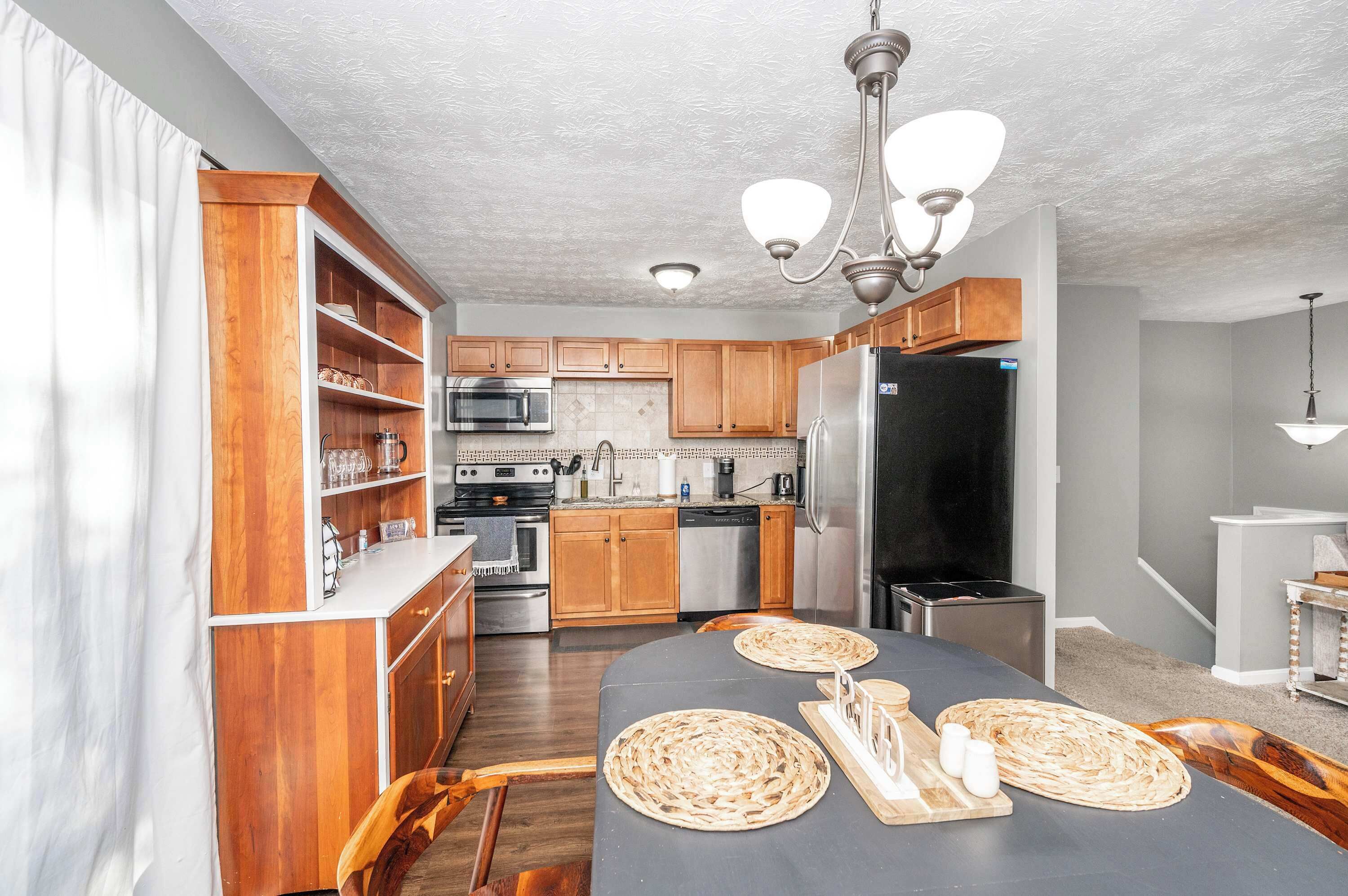 A modern kitchen with wooden cabinets, stainless steel appliances, and a dining area with woven placemats.