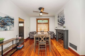 A dining area with a wooden table and chairs, a ceiling fan, a stained glass window, and a fireplace. - Historic 4BR | Walk Bellevue | 5 Min to Cincy (Dayton)