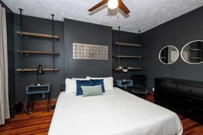A modern bedroom with a large bed, a ceiling fan, and built-in shelves.