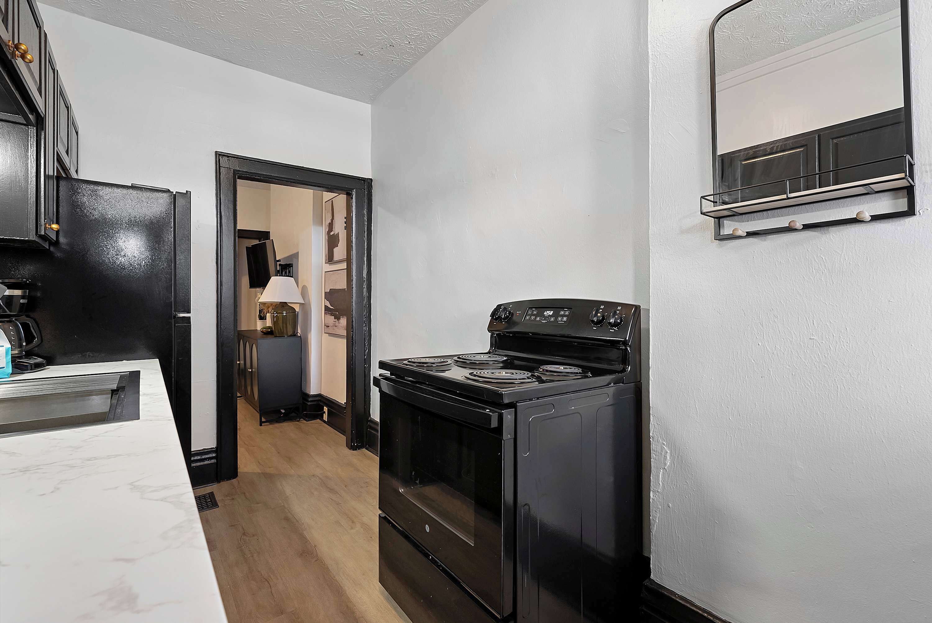 A kitchen with a black stove, white cabinets, and a marble countertop.