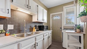 A kitchen with white cabinets, a double sink, a microwave, and a stove. - Merion Village Residences 1164.5 (Columbus)