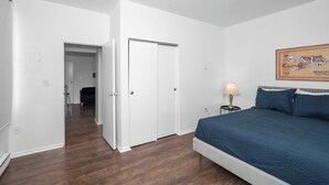 A bedroom with a bed, a nightstand, a lamp, and a framed picture on the wall. - Northside Suites 3 – A Chic, Relaxed Stay for 2 (Cincinnati)