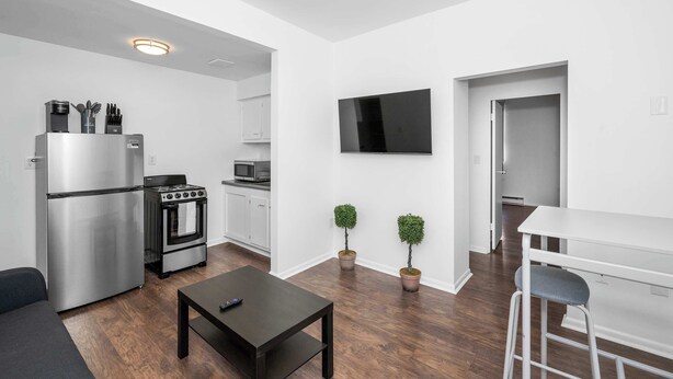 A modern kitchen with stainless steel appliances, a flat-screen TV, and a dining area with a bar stool. - Northside Suites 3 – A Chic, Relaxed Stay for 2 (Cincinnati)