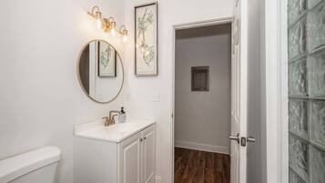 A bathroom with a white sink, a round mirror, and wall-mounted lights.