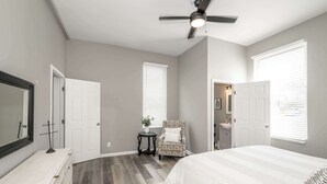 Une chambre à coucher comprenant un lit, une chaise, une coiffeuse et un ventilateur de plafond.