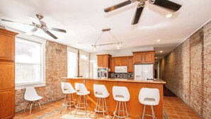 A kitchen with a bar area, wooden cabinets, and a brick wall. - Sweet Escape (Cincinnati)