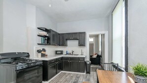 A modern kitchen with dark cabinetry, a stainless steel stove, and a wooden dining table. - Chic, Modern Gem with Style (Cincinnati)