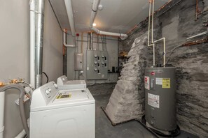 A laundry area with a washing machine, a water heater, and a utility room with electrical panels. - Queen City Views 2 – Sleeps 2! (Cincinnati)