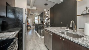 A modern kitchen with dark cabinetry, granite countertops, and stainless steel appliances. - Queen City Views 2 – Sleeps 2! (Cincinnati)