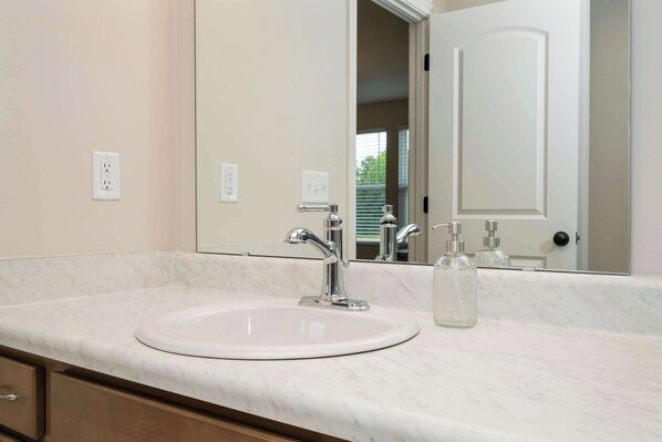Une salle de bain avec un lavabo blanc, un miroir et une porte.