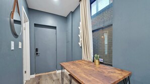 Una habitación con una mesa de madera, una puerta y una ventana con cortinas.