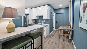 Una cocina moderna con armarios blancos, una mesa de comedor de madera y una barra con taburetes.