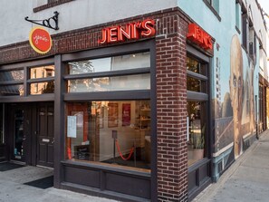 Une devanture de magasin avec une enseigne « JENIS » bien visible, de grandes vitrines et une façade en briques.