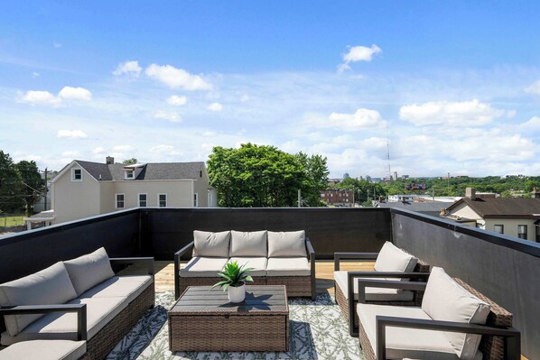 A rooftop patio with outdoor furniture, a potted plant, and a view of the cityscape. - Heights on Wayne by Blackhouse (Cincinnati)