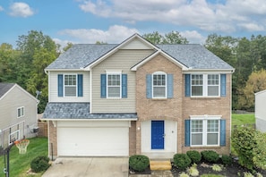 A two-story house with a garage, a blue front door, and a brick facade.