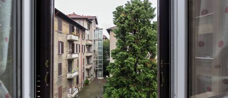A view from a window of a building with multiple floors, balconies, and a tree in the foreground.