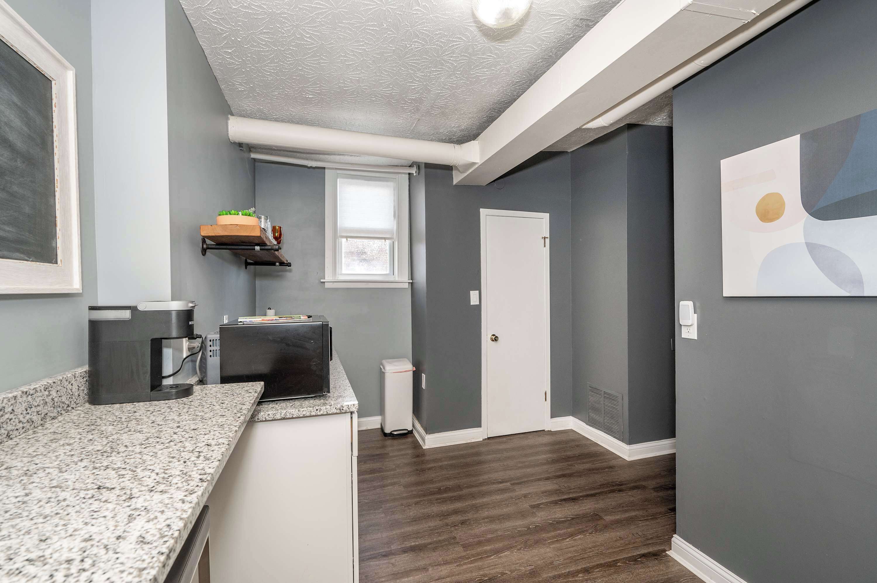 A modern kitchen with granite countertops, a coffee maker, and a small window.