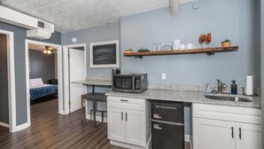 A compact kitchen with white cabinets, a microwave, and a dishwasher.