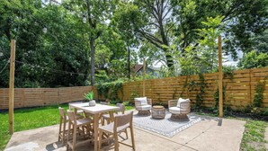 An outdoor patio with a concrete floor, surrounded by a wooden fence and lush greenery. - Woodburn Villa by Blackhouse (Cincinnati)