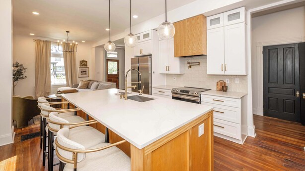 A modern kitchen with a large island, white cabinetry, stainless steel appliances, and pendant lighting. - Woodburn Villa by Blackhouse (Cincinnati)
