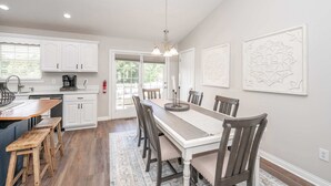 Een moderne keuken met witte kasten, een houten eettafel en een kroonluchter.