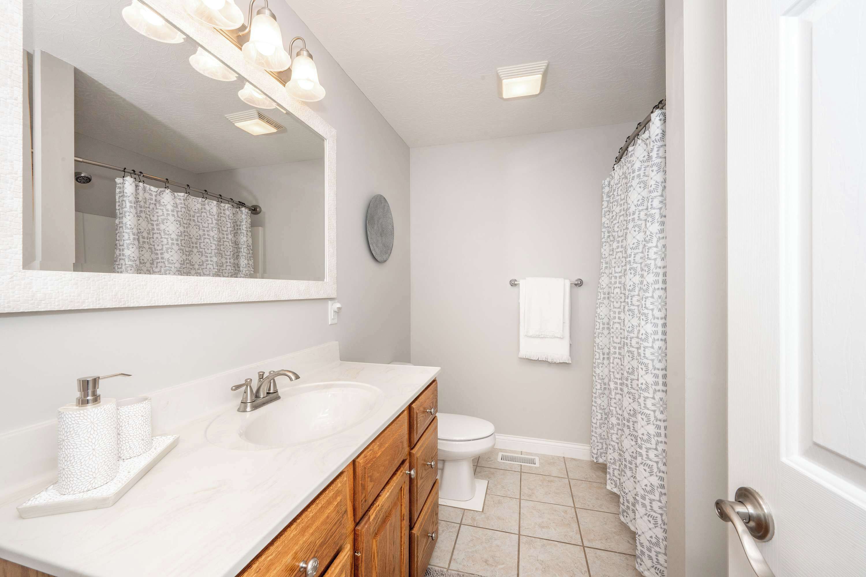 A bathroom with a double sink vanity, a toilet, and a shower curtain.