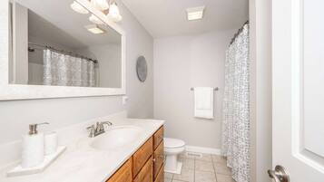 A bathroom with a double sink vanity, a toilet, and a shower curtain.