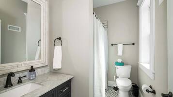 A bathroom with a marble sink, black faucet, and a white toilet.
