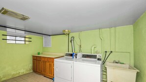 Una sala de lavandería con lavadora, lavamanos y ventana.