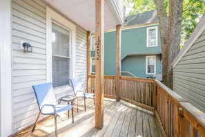 A wooden deck with two chairs, a railing, and a house number 3202.