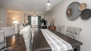 Un espace repas moderne avec une longue table, des chaises à revêtement gris et un ventilateur de plafond.