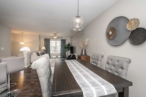 A modern dining area with a long table, grey upholstered chairs, and a ceiling fan. - The Gem Vacation Rental! (Walton)