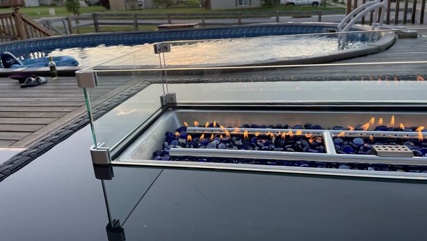 Un espace piscine sur le toit, doté d’une structure en verre, d’un jacuzzi et d’un foyer.