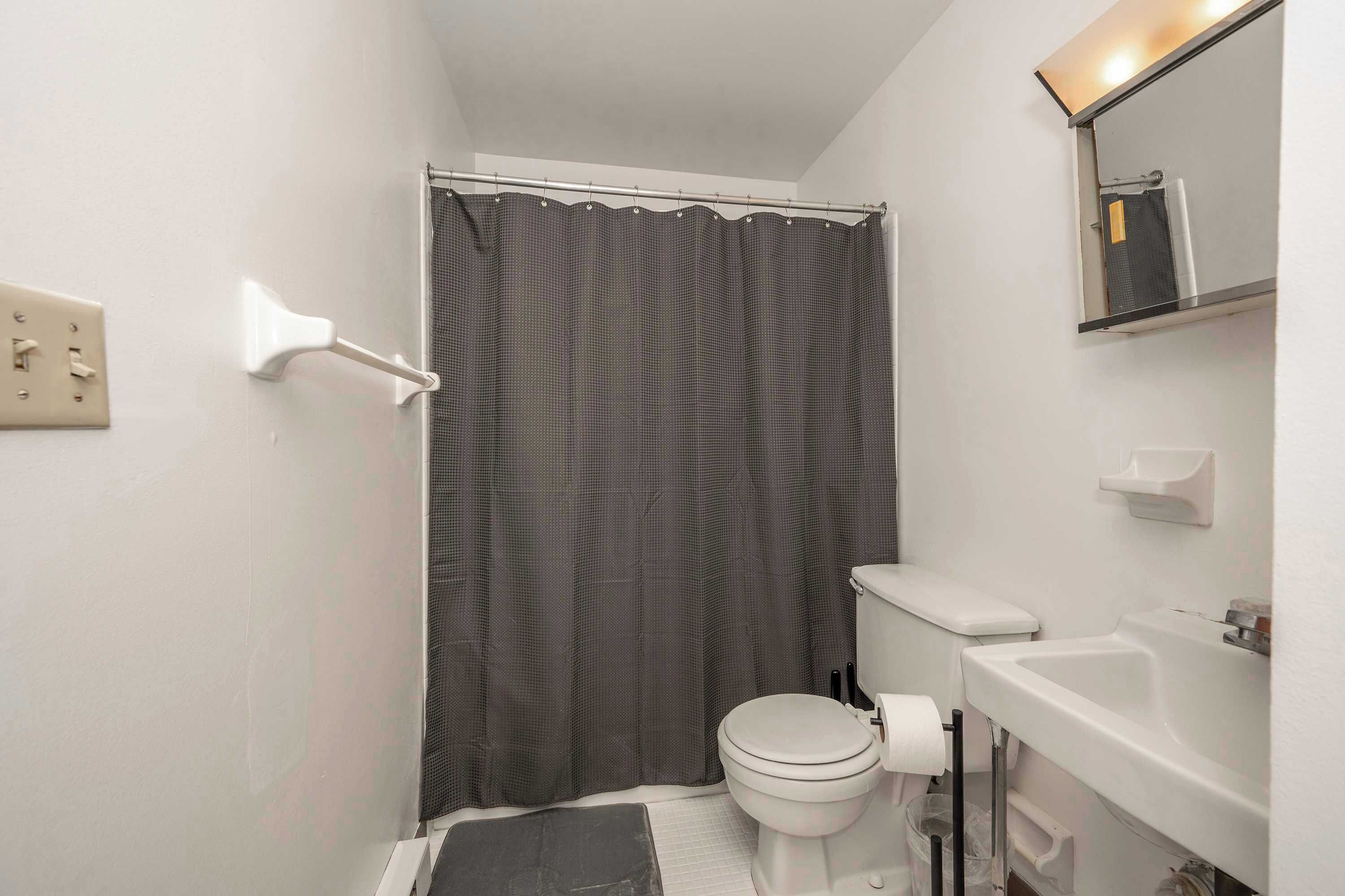 A small bathroom with a toilet, sink, and shower curtain.